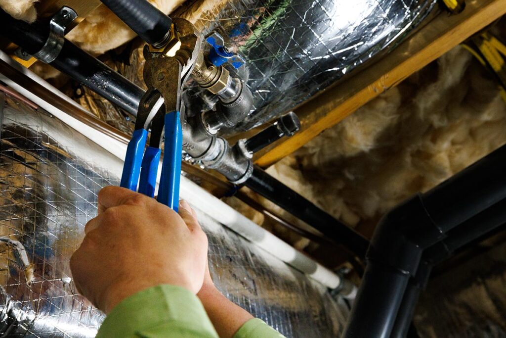 Plumber using wrench to adjust pipes